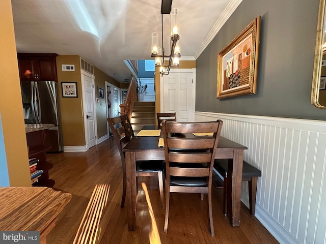 dining area featuring dark wood-type flooring, ornamental molding, and a chandelier