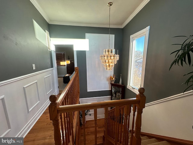 stairway featuring hardwood / wood-style flooring, crown molding, and a notable chandelier