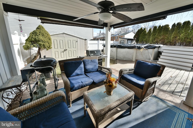 deck with a storage shed, an outdoor living space, grilling area, and ceiling fan