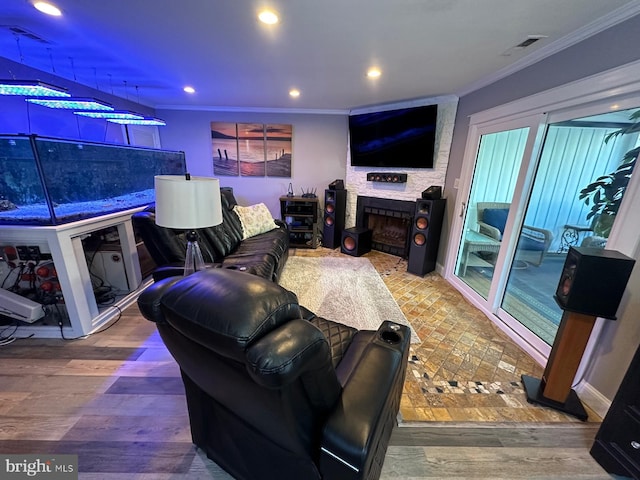 living room featuring hardwood / wood-style flooring, ornamental molding, and a stone fireplace