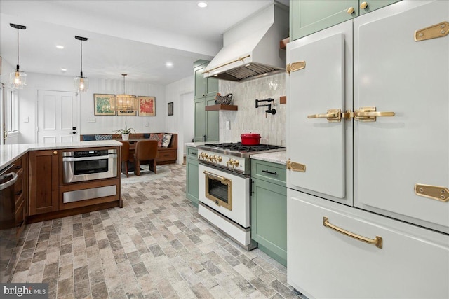 kitchen featuring white appliances, hanging light fixtures, green cabinets, and custom range hood