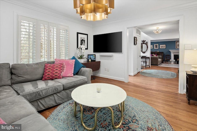 living room featuring an inviting chandelier, ornamental molding, and hardwood / wood-style floors