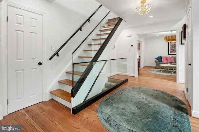 stairs featuring hardwood / wood-style floors and a notable chandelier