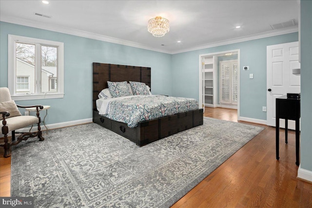 bedroom with ornamental molding, hardwood / wood-style floors, and a chandelier