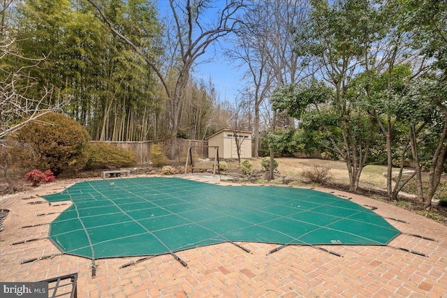 view of swimming pool featuring a shed and a patio area