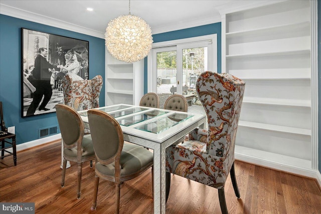 dining room featuring crown molding, hardwood / wood-style floors, built in features, and an inviting chandelier