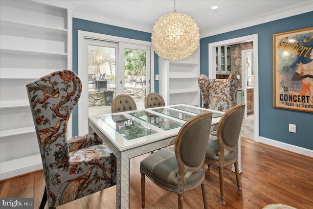 dining space featuring hardwood / wood-style flooring, built in features, ornamental molding, and a chandelier