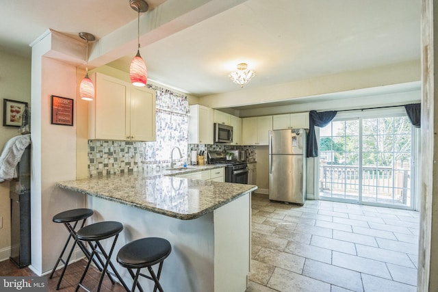 kitchen featuring pendant lighting, sink, appliances with stainless steel finishes, tasteful backsplash, and kitchen peninsula