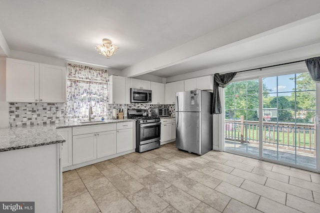 kitchen featuring stainless steel appliances, white cabinetry, sink, and backsplash