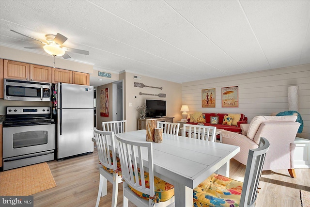 dining area featuring ceiling fan, ornamental molding, a textured ceiling, and light wood-type flooring