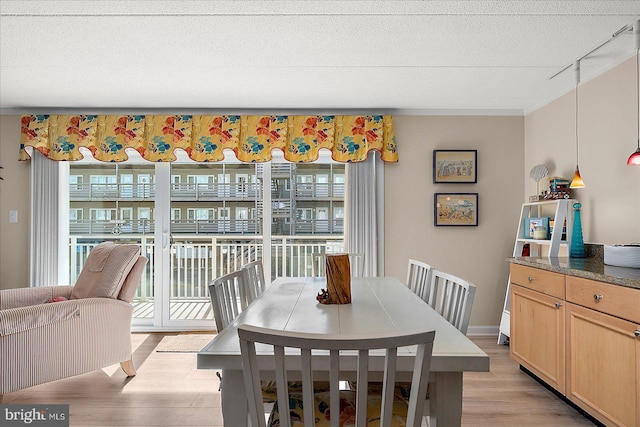 dining area with a textured ceiling, light hardwood / wood-style flooring, and a wealth of natural light