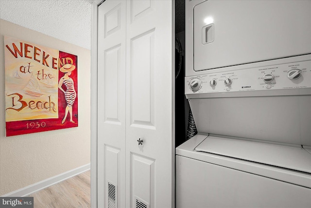 laundry room with stacked washer and clothes dryer and light wood-type flooring