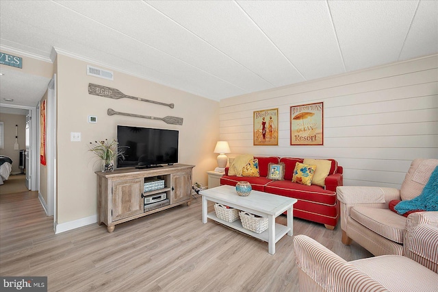 living room with ornamental molding and light hardwood / wood-style floors