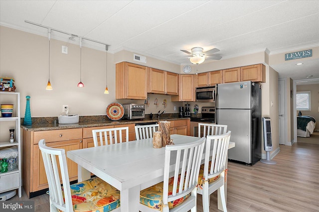 kitchen with crown molding, decorative light fixtures, dark stone countertops, light wood-type flooring, and appliances with stainless steel finishes