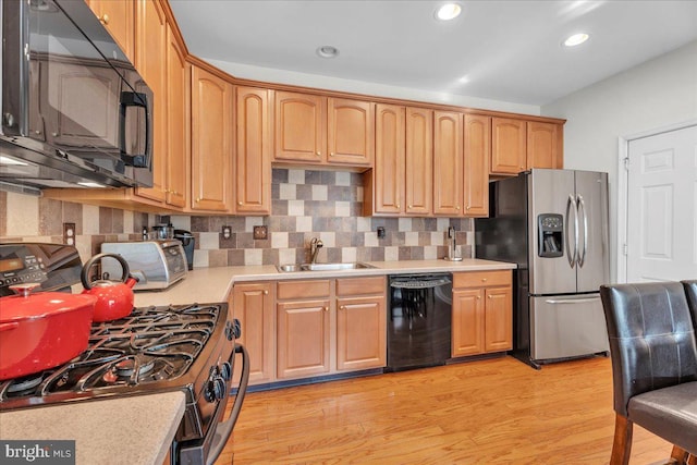 kitchen featuring backsplash, light hardwood / wood-style floors, sink, and black appliances