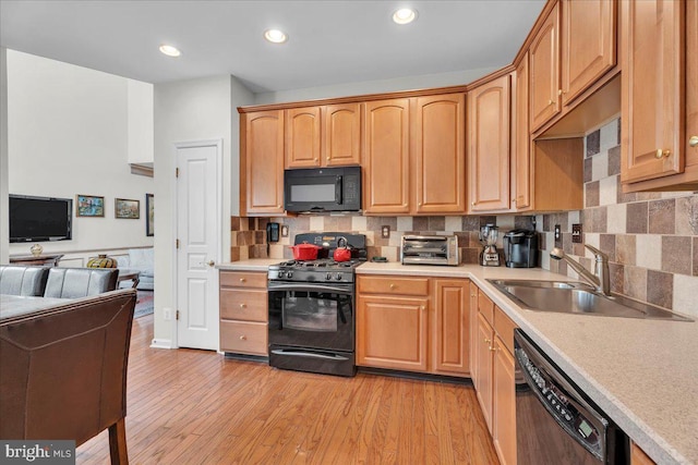 kitchen featuring sink, decorative backsplash, light wood-type flooring, and black appliances