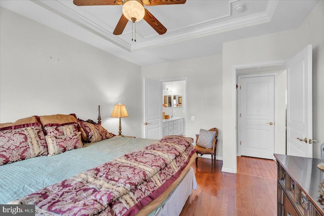 bedroom with ensuite bathroom, wood-type flooring, ornamental molding, a tray ceiling, and ceiling fan