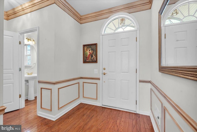 foyer with ornamental molding and light wood-type flooring