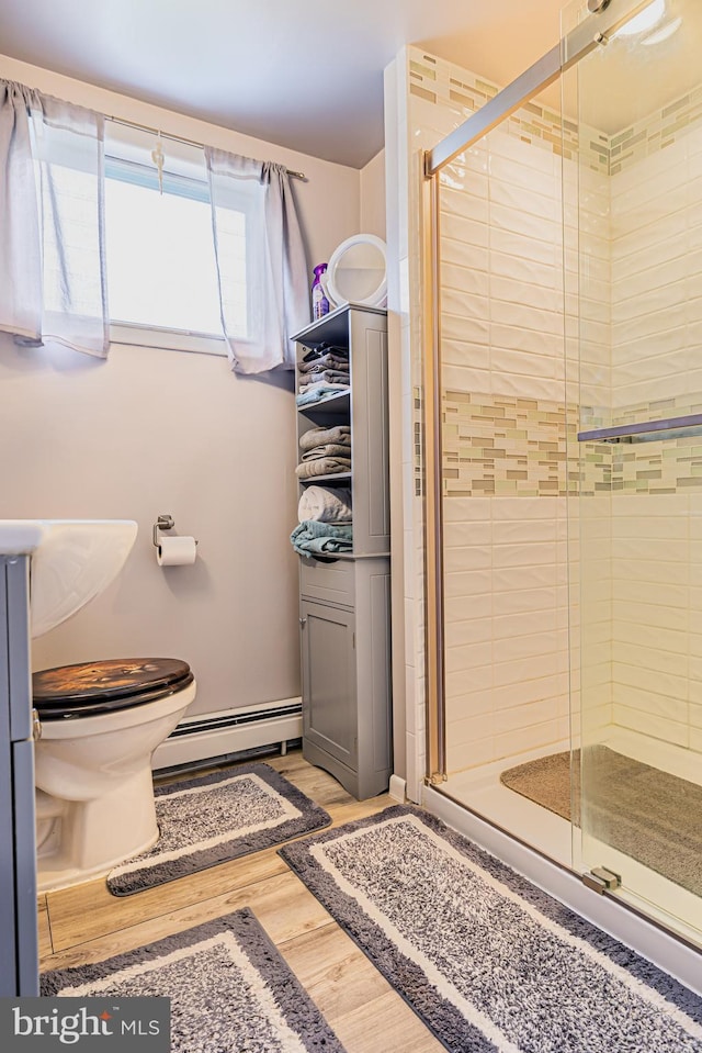 bathroom with a baseboard radiator, wood-type flooring, toilet, and a shower with shower door