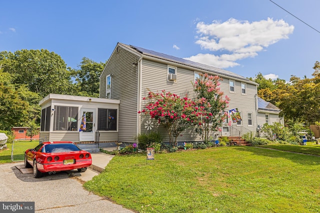 rear view of house featuring a yard and a sunroom