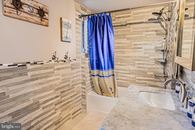 bathroom featuring tile walls, vanity, and shower / bath combo with shower curtain