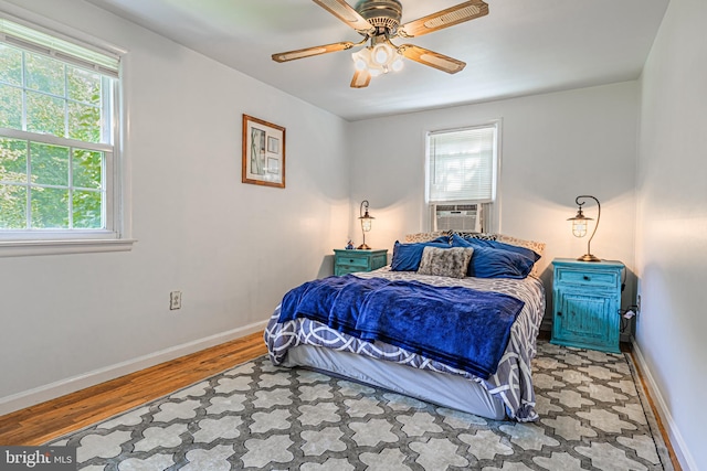 bedroom featuring cooling unit, ceiling fan, and light wood-type flooring