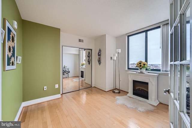 unfurnished living room with a textured ceiling and light wood-type flooring