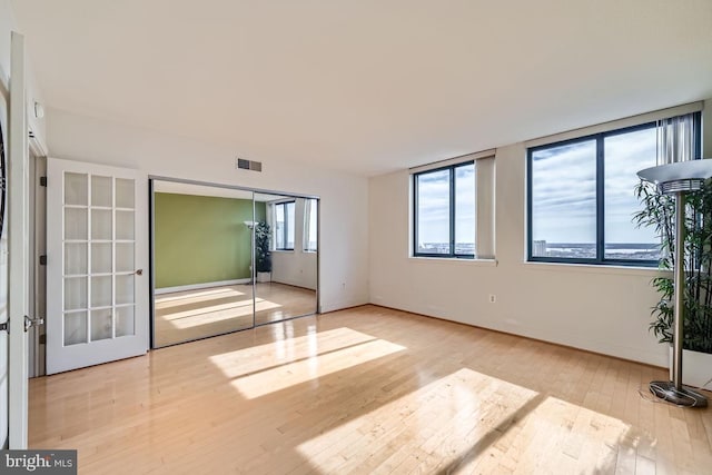 unfurnished bedroom featuring french doors, a closet, and light hardwood / wood-style flooring