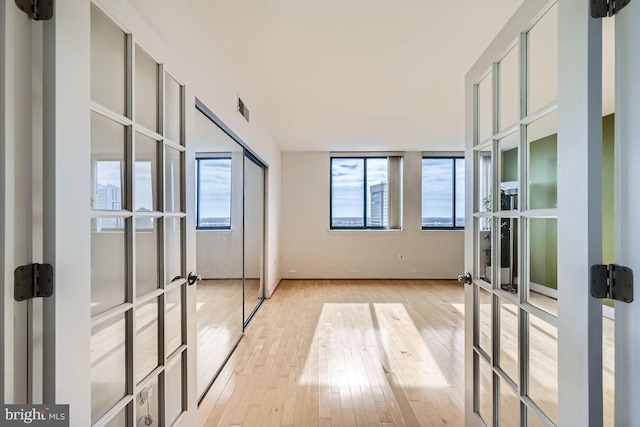 unfurnished room featuring french doors and light wood-type flooring