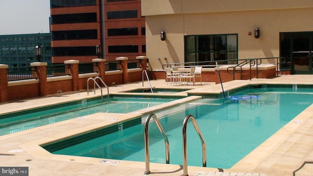 view of swimming pool with a hot tub and a patio area