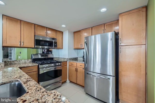 kitchen featuring stainless steel appliances, light stone countertops, and light tile patterned floors