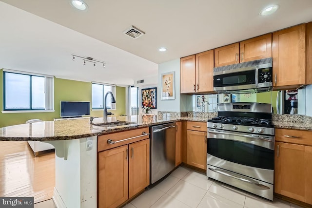 kitchen featuring light stone countertops, appliances with stainless steel finishes, sink, and kitchen peninsula