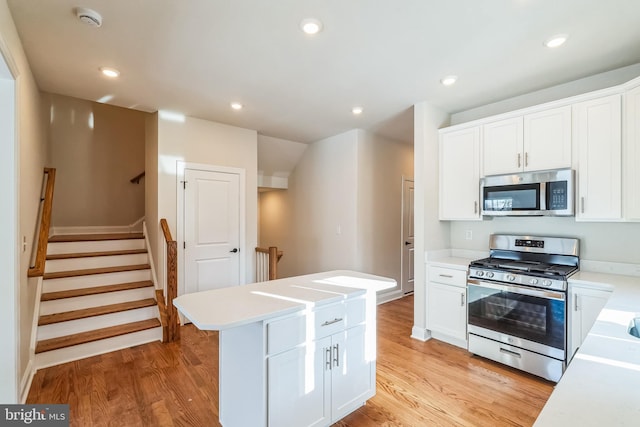 kitchen featuring white cabinetry, appliances with stainless steel finishes, a center island, and light wood-type flooring