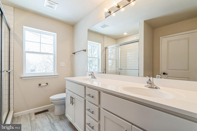 bathroom with vanity, toilet, and a shower with door