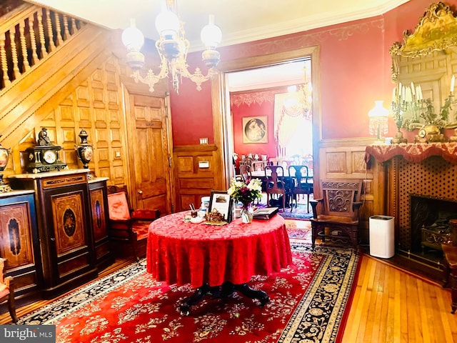 living area featuring a tile fireplace, hardwood / wood-style floors, a notable chandelier, and crown molding