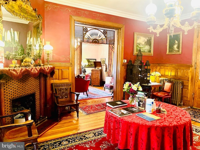 dining room featuring hardwood / wood-style flooring, ornamental molding, radiator heating unit, and an inviting chandelier