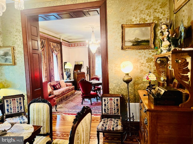 living area with a healthy amount of sunlight, hardwood / wood-style flooring, and a chandelier