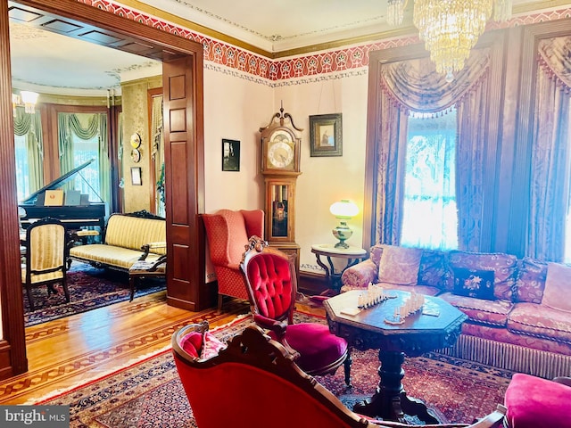 living room featuring ornamental molding, wood-type flooring, and a chandelier