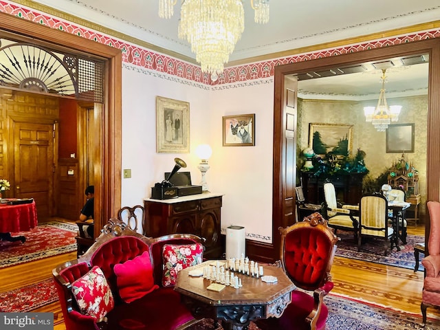 living area with an inviting chandelier, wood-type flooring, and crown molding