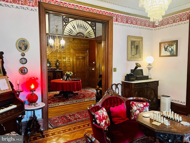 living area with ornamental molding and a chandelier