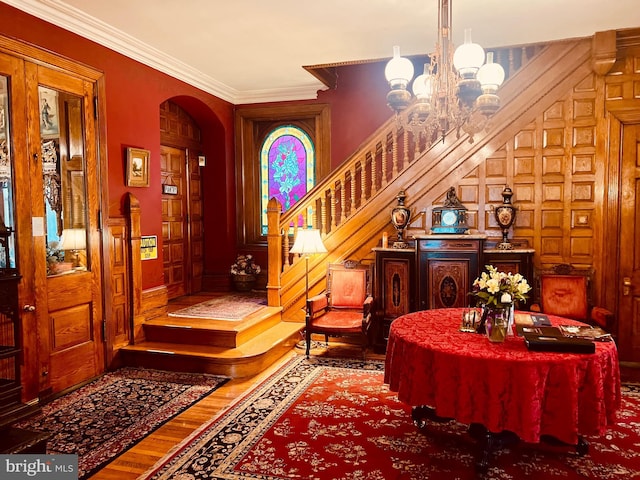 foyer entrance with crown molding, wood-type flooring, and a chandelier