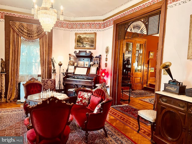 living area featuring crown molding, wood-type flooring, and an inviting chandelier