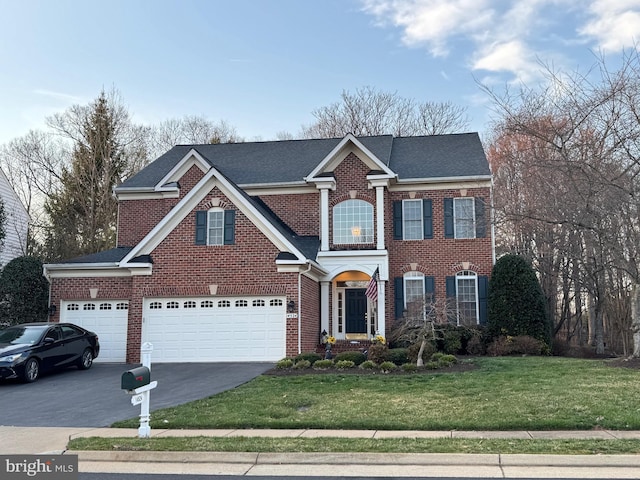 georgian-style home featuring a front lawn, aphalt driveway, roof with shingles, a garage, and brick siding