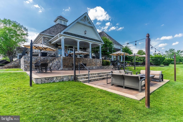 rear view of property featuring stone siding, a lawn, an outdoor hangout area, and a patio