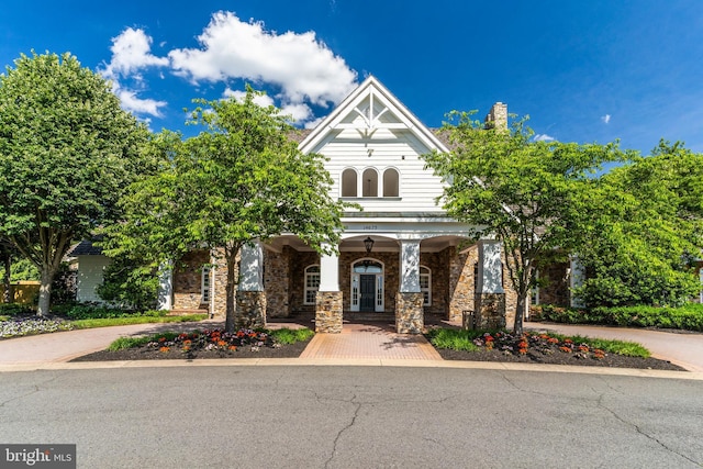 view of front of home with stone siding, french doors, and a chimney