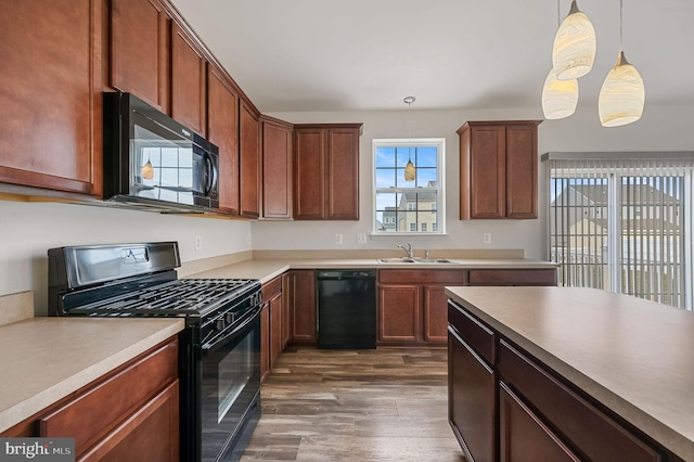 kitchen featuring hanging light fixtures, sink, dark hardwood / wood-style flooring, and black appliances