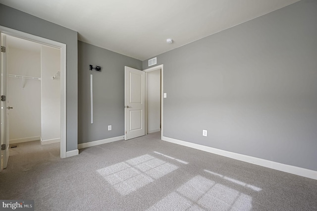 unfurnished bedroom with light colored carpet and a closet