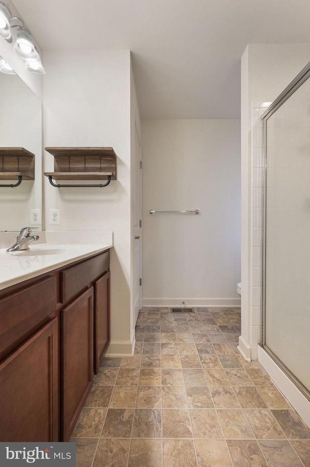 bathroom featuring vanity, toilet, and a shower with door