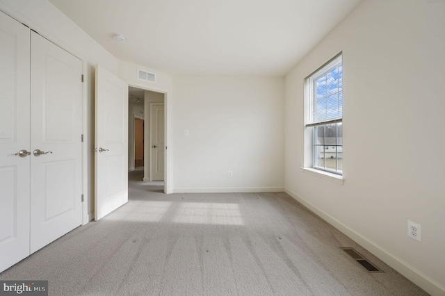 unfurnished bedroom featuring a closet and light carpet