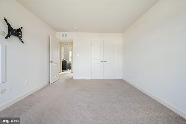 unfurnished bedroom featuring light colored carpet and a closet